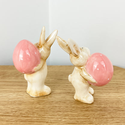 Pair of Cute Easter Bunnies Holding Eggs