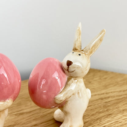 Pair of Cute Easter Bunnies Holding Eggs